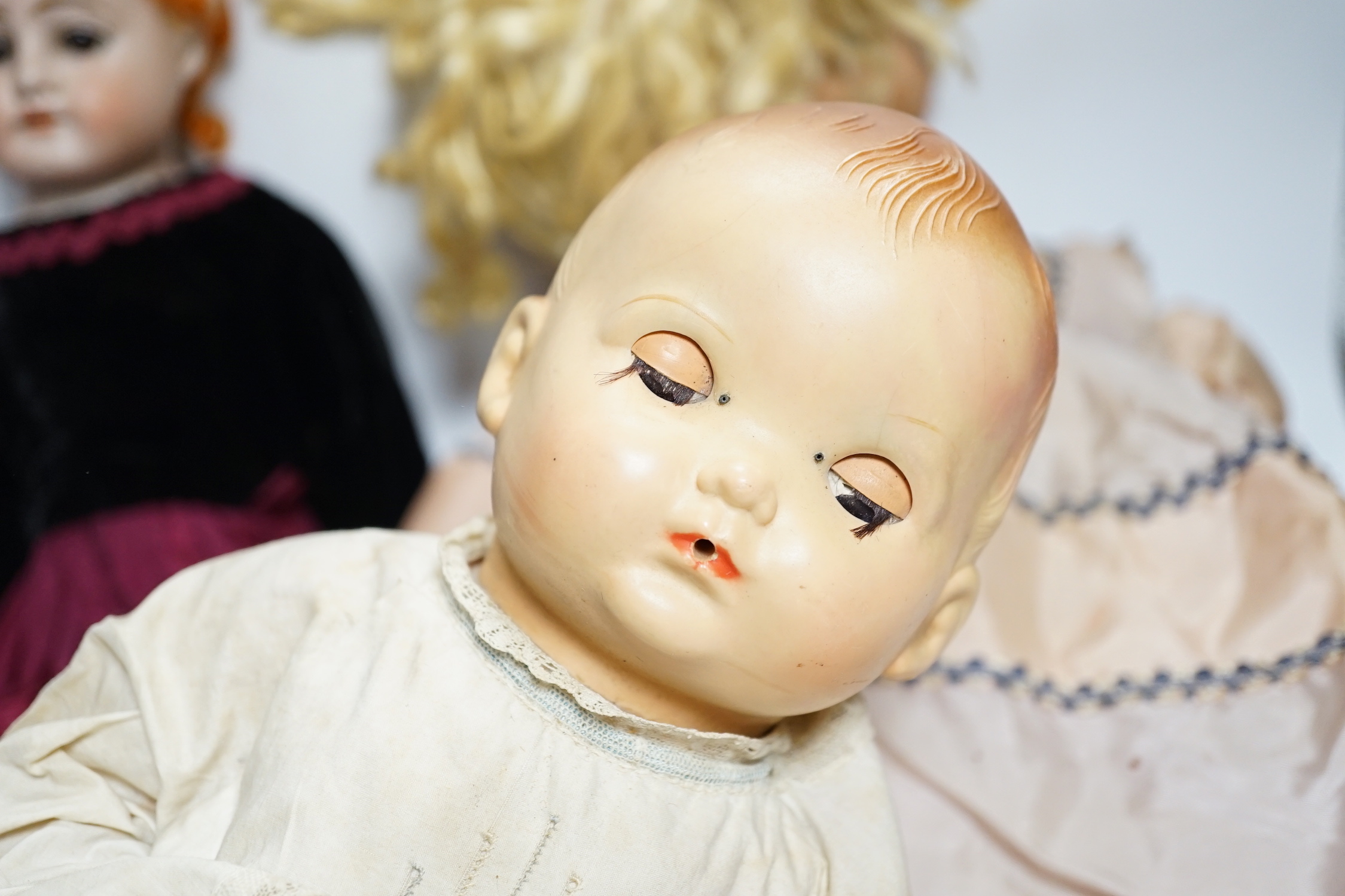 Three dolls; a German Bisque shoulder head doll with sleeping eyes with jointed kid leather body, 46cm, an English celluloid doll and another